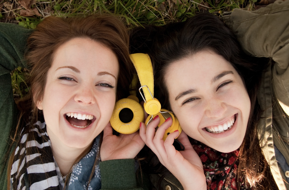 two girls sharing a pair of headphones