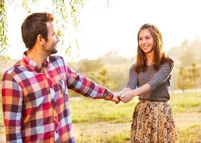 male and female couple holding hands near a tree