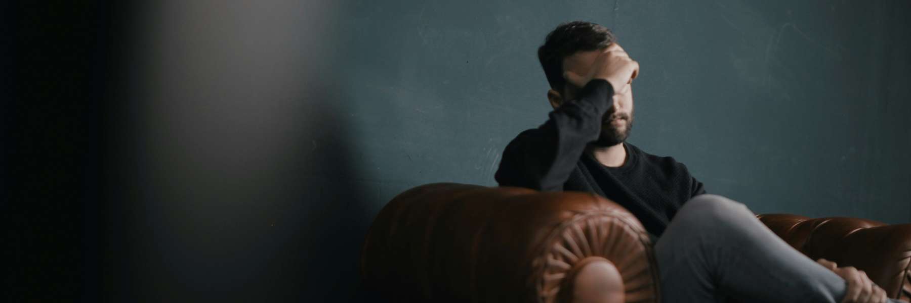 stressed man holding hand against forehead 