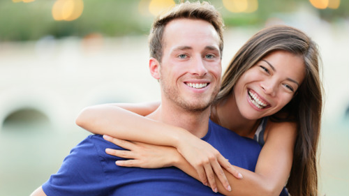 woman hugging her male partner's shoulders from behind