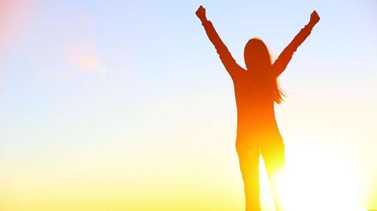 silhouette of woman with her arms up in the air