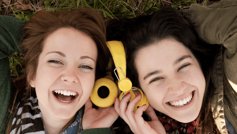 woman and her girlfriend sharing headphones while listening to music