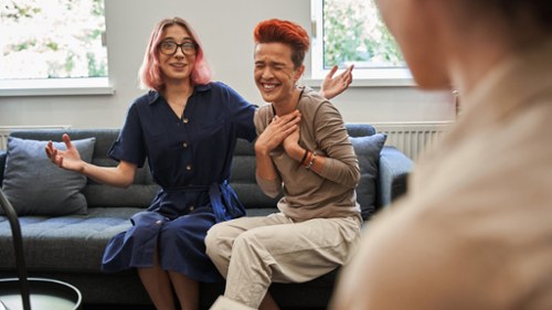 woman and her girlfriend laughing on couch during therapy