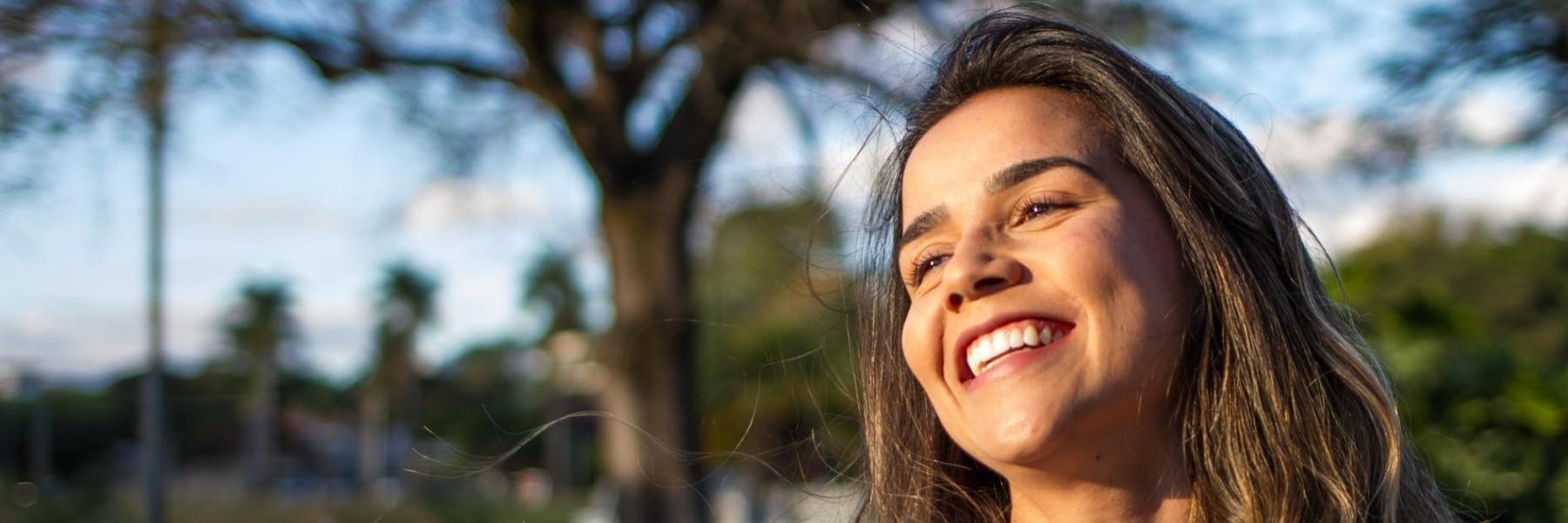 federal way woman smiling in sunlight with trees behind