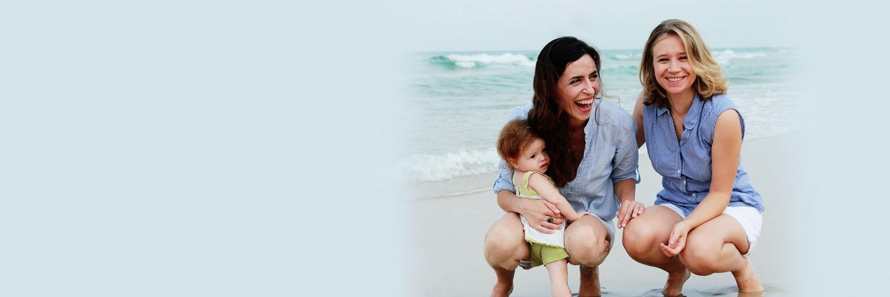 a female couple laughing on a beach with their child in tacoma