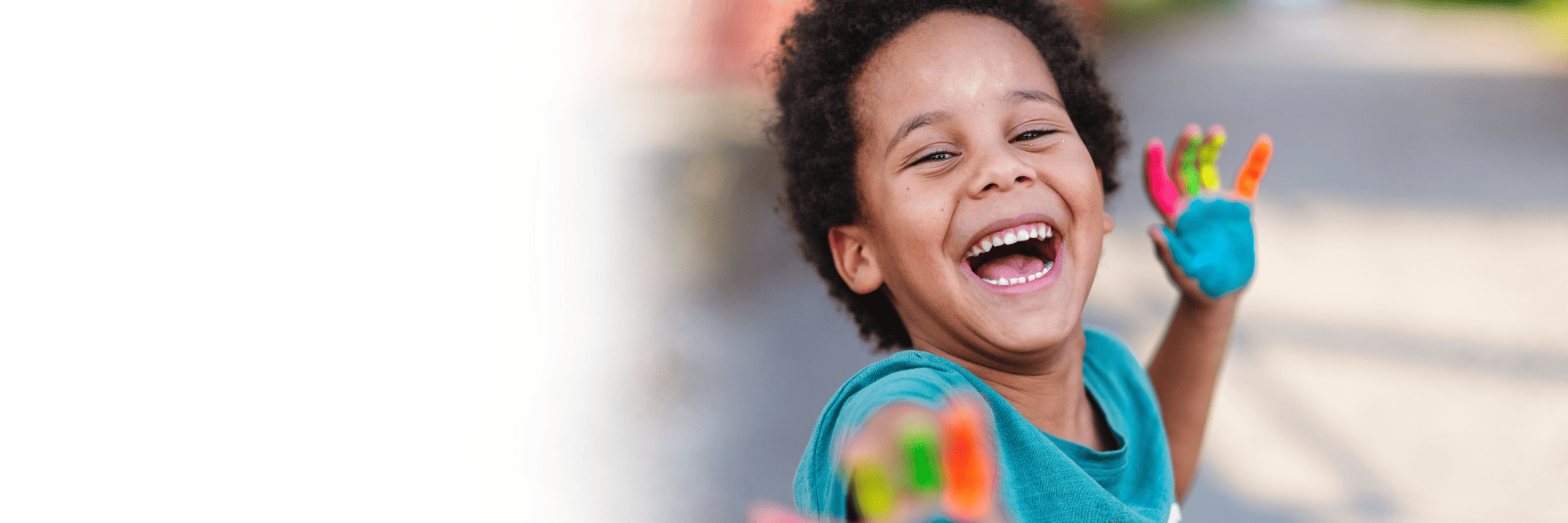 Neurodiverse young boy with painted hands smiling
